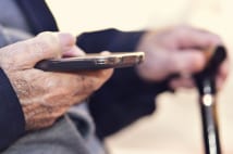 nito500151100143.jpg - closeup of an old caucasian man with a walking stick in his hand using a smartphone