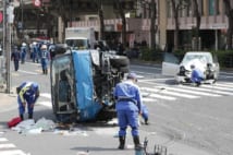 ごみ収集車と乗用車が衝突し、歩行者がはねられた事故現場を調べる警察官（時事通信フォト）