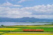 島根県　北松江線の一畑電車。湖畔を望み、田園を走るオレンジ色の小さな電車