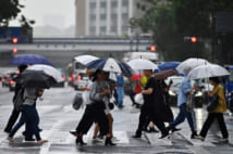 People corss a street during a rainy afternoon in Tokyo on May 21, 2019. (Photo by Charly TRIBALLEAU / AFP)