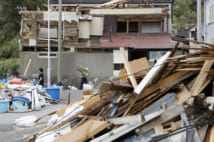 台風１５号の影響で屋根や壁が壊れた家屋と積み上げられたがれき（千葉県鋸南町　共同通信社）