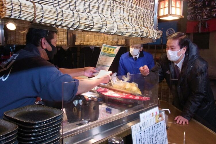 千葉県船橋市の居酒屋店主（左）に営業時間短縮を要請するチラシを渡す千葉県の森田健作知事（右）（時事通信フォト）