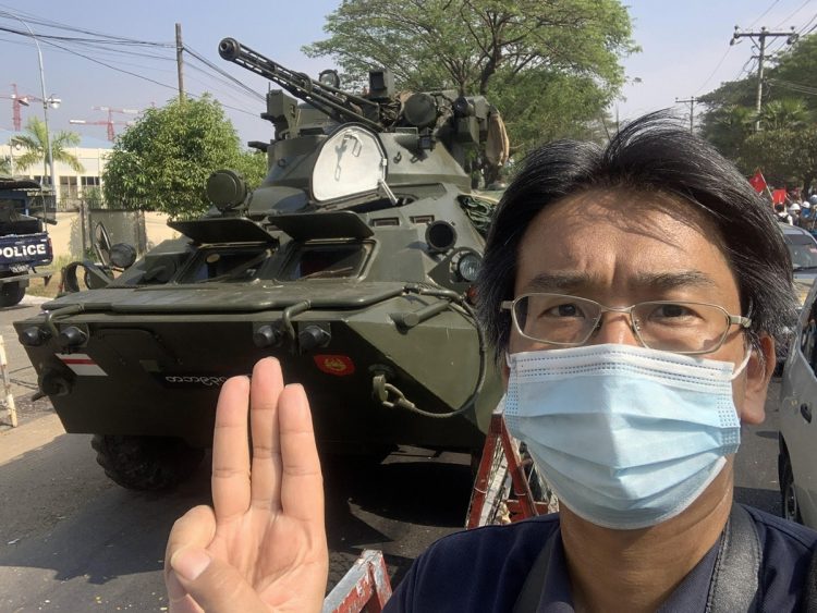 軍の装甲車の前で「3本指」を立ててクーデターに反対の意思表示をする北角さん （写真／北角裕樹さん提供）