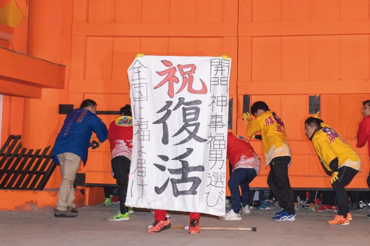 開門の直前、開門神事講社の平尾亮代表が3年ぶりの神事復活を祝う幕を掲げた