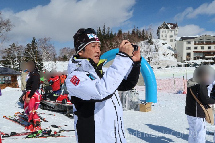スキー場でカメラを構える神田正輝（『神田正輝カップ』公式サイトより）