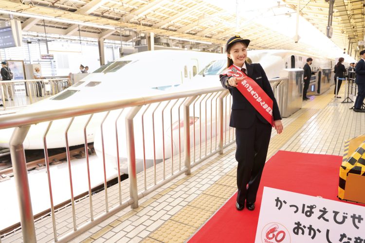 東京駅17番ホームで「Zポーズ」で出発を宣言する“百田車掌”。隣のホームには、「目撃すると幸運が訪れる」という「ドクターイエロー」が停車。1か月に3回だけしか走行しないため、貴重な偶然に百田も大興奮！