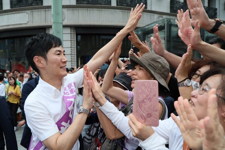 銀座四丁目交差点で街頭演説を終え、聴衆らとハイタッチを交わす前広島県安芸高田市長の石丸伸二候補（左）。6月30日（時事通信フォト）