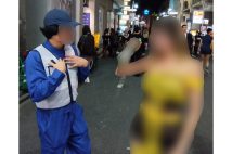 チャミスルを手にした女性に警備員のコスプレをした男性が話しかける