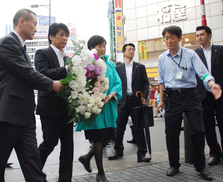 危険ドラッグを吸った男が車を暴走させた事件現場で、献花に向かう田村憲久厚生労働相（左から2人目）、小池百合子衆院議員（同3人目）ら。肩書きは当時。この事故をきっかけに社会問題として大きな関心を集め「危険ドラッグ」という呼称が定まった（時事通信フォト）