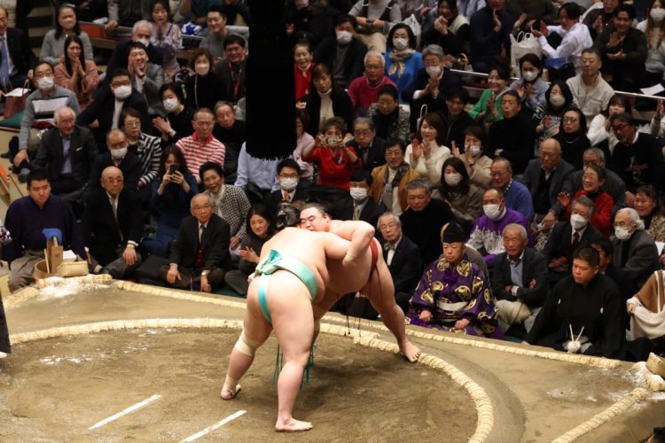 初場所初日、土俵上に声援を送る着物美人。鮮やかな緑色の着物姿だ