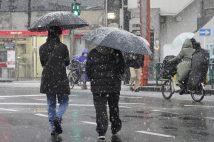 雪が降る都心を歩く人たち。2月5日、「最強寒波」の影響で東京23区を含む平地でも雪が積もった（時事通信フォト）