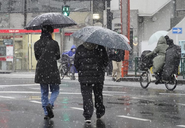 雪が降る都心を歩く人たち。2月5日、「最強寒波」の影響で東京23区を含む平地でも雪が積もった（時事通信フォト）